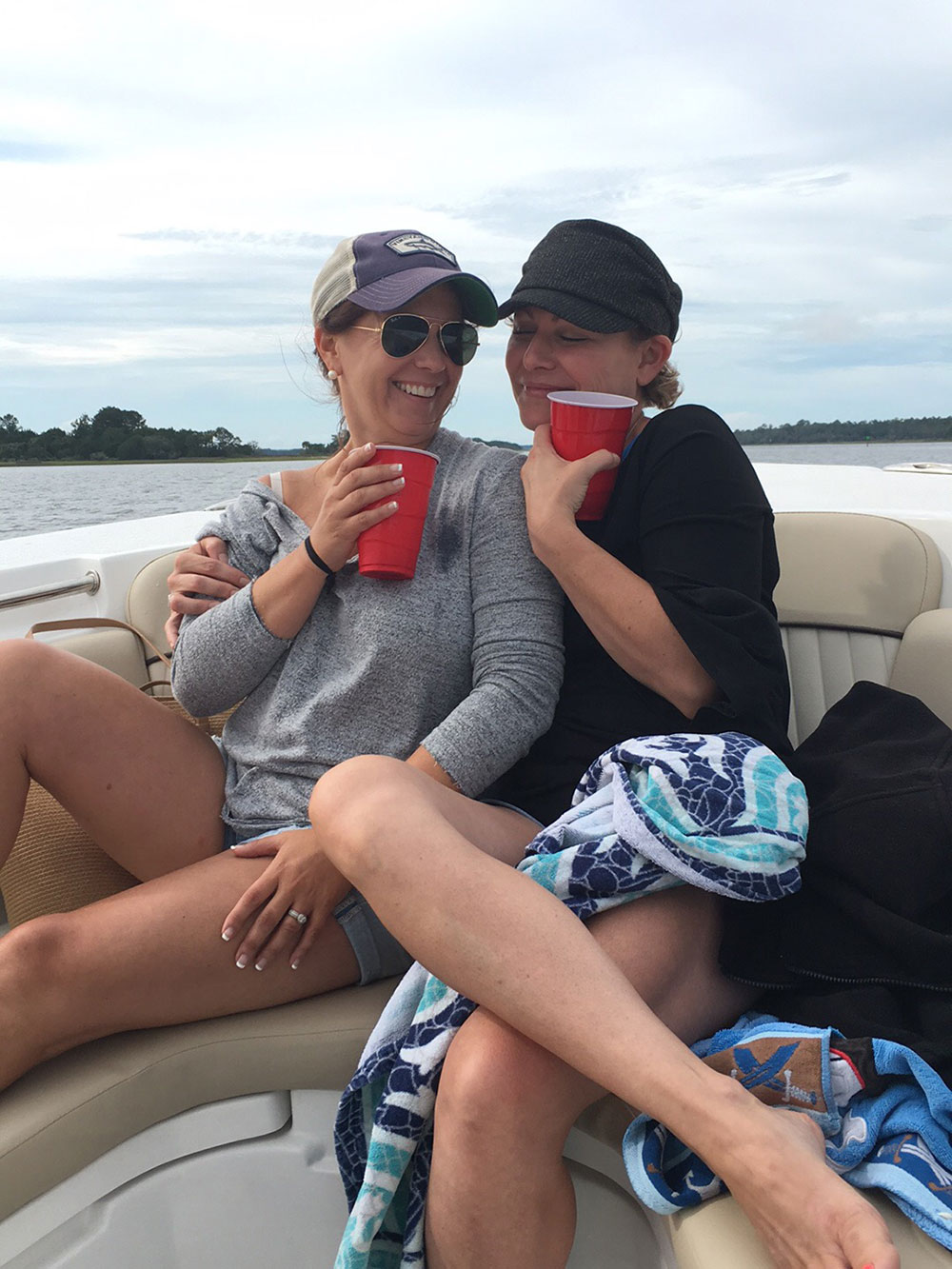 Two women with red plastic drink cups sitting together on a boat