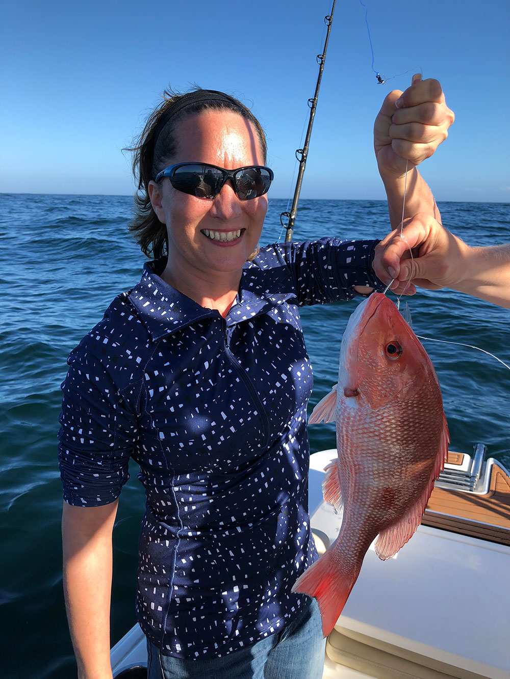 smiling woman holds up red fish