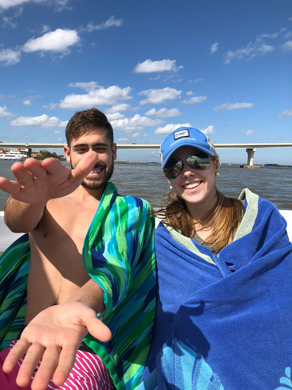 Teenage boy making alligator hand gesture sitting next to girl wrapped in a towel