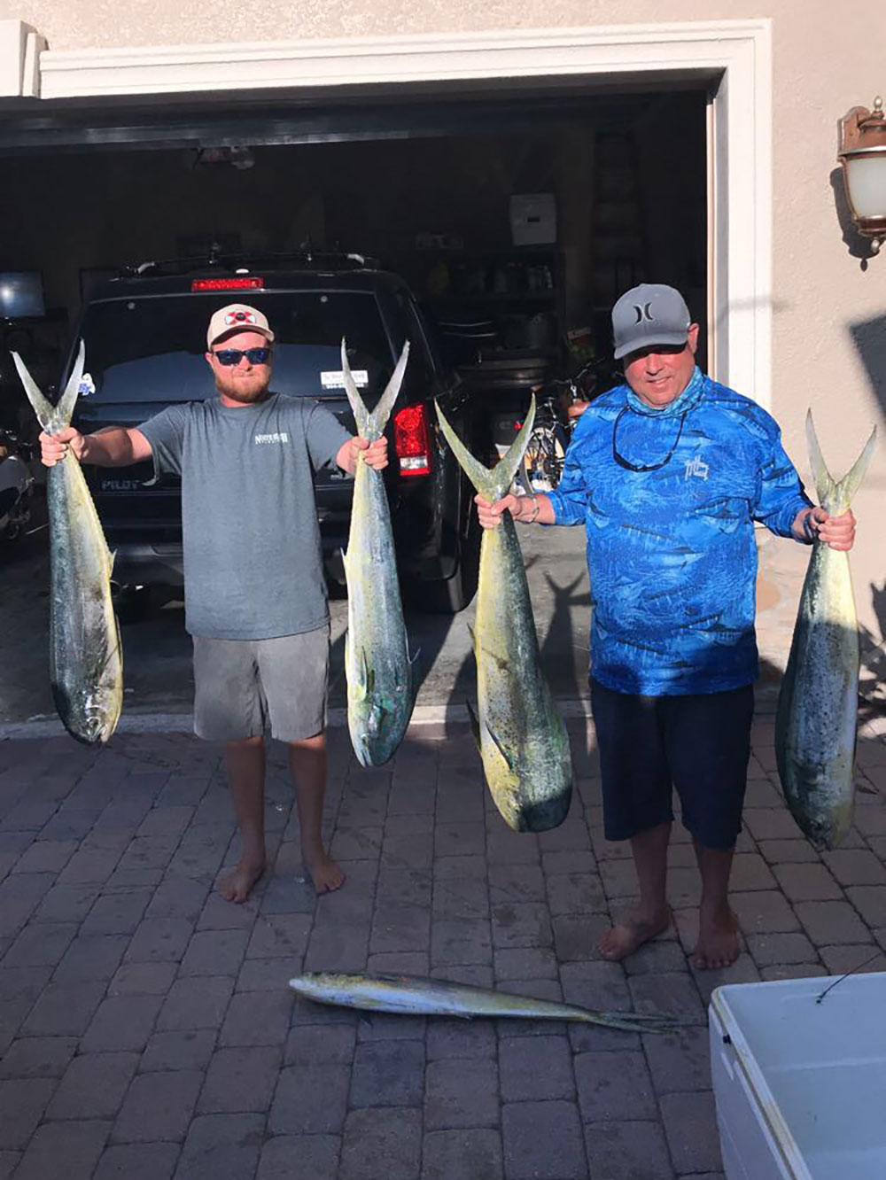 Chris Worth and first mate each holding up 2 Mahi fish
