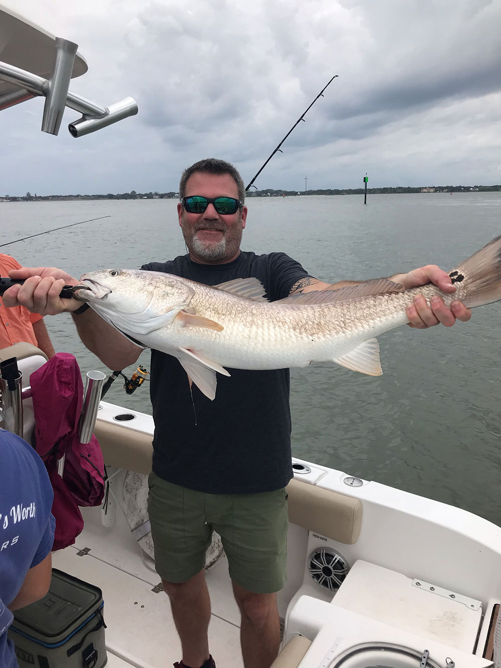 man showcases white and brown fish on the boat