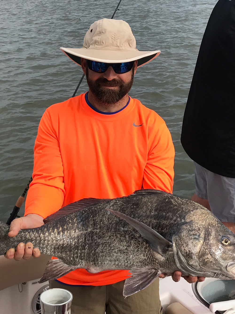 man holds large fish on the boat