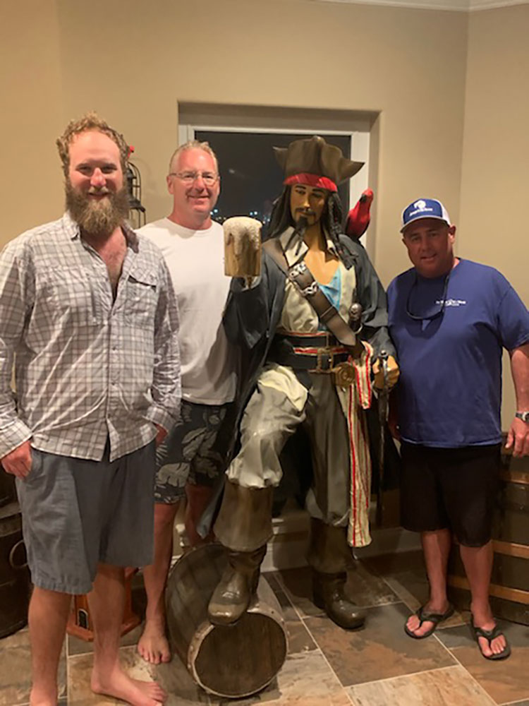 Chris Worth and guests standing next to a pirate statue