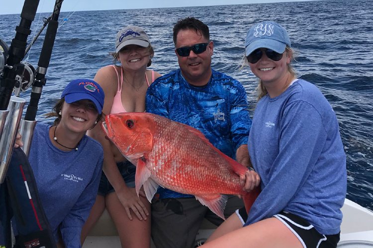 Chris Worth and team holding a red snapper on a fishing charter